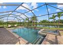 Inviting screened-in pool and spa area with a serene lake view surrounded by lush landscaping at 20831 Valprato Ct, Venice, FL 34293
