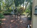 Outdoor patio with brick flooring, lush landscaping, and a dining table providing a relaxing space at 2181 Pine Gardens Trl, Sarasota, FL 34231