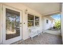 Covered porch with tiled flooring, decorated with a small white table and chair set by a leaded glass front door at 2606 Bismark Way, Sarasota, FL 34231