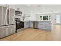 A modern kitchen featuring stainless appliances, light blue lower cabinets, white upper cabinets, and wood flooring at 2655 Bay St, Sarasota, FL 34237