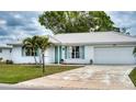 Bright white single-story home with turquoise shutters, a paver walkway, and a wide driveway leading to an attached garage at 4102 Lakewood Ave, Bradenton, FL 34208