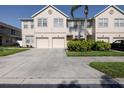 View of townhome featuring a two-car garage, well-maintained lawn, and mature landscaping at 4103 Foristall Ave # 4103, Sarasota, FL 34233
