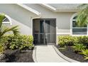 Close-up of a home's front door surrounded by lush bushes and a curved sidewalk at 5750 Carriage Dr, Sarasota, FL 34243