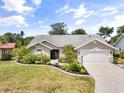 Daytime view of a charming single-story home with a well-manicured lawn, a two car garage and lush tropical landscaping at 5750 Carriage Dr, Sarasota, FL 34243