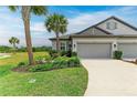 Green lawn leads to a two-car garage, with lush landscaping with palm trees in front of the townhome at 6094 Amberly Dr, Bradenton, FL 34208