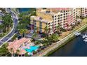 Aerial view of condo building with community pool, parking, and waterway access at 610 Riviera Dunes Way # 308, Palmetto, FL 34221