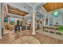 Open living room features high ceilings, wood beam accents, columns, and seamless access to the lanai at 8105 Warwick Gardens Ln, University Park, FL 34201