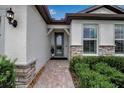 Inviting entryway with stone accents, a covered porch, and manicured landscaping at 10414 Spring Tide Way, Parrish, FL 34219