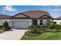 Charming single-Gathering home featuring a well-manicured lawn, lush landscaping, and a paver driveway at 10414 Spring Tide Way, Parrish, FL 34219