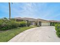 Attractive single-story home with stone accents, a wide driveway, and lush green landscaping at 1227 Waterside Ln, Venice, FL 34285