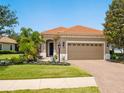 Charming single-story home showcasing a terracotta tile roof, brick driveway, and well-manicured lawn at 14325 Stirling Dr, Lakewood Ranch, FL 34202