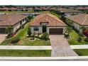 Aerial view of a home featuring a red tile roof, green lawn, and a community pond at 20542 Trattoria Loop, Venice, FL 34293
