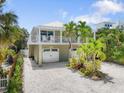 Stunning home with well-manicured landscaping, a double garage, and a charming balcony, creating a welcoming entrance at 229 S Harbor Dr, Holmes Beach, FL 34217