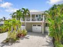 Charming two-story home with a white picket fence, double garage and tropical landscaping for curb appeal at 229 S Harbor Dr, Holmes Beach, FL 34217