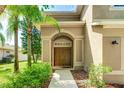 Inviting front entrance featuring double doors, an arched entryway, and lush landscaping with palm trees at 3303 Pine Top Dr, Valrico, FL 33594