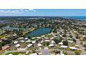Wide aerial shot of a home located near a lake, surrounded by homes and greenery at 445 Matisse S Cir # 445, Nokomis, FL 34275
