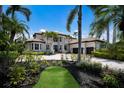 Elegant home showcasing tropical landscaping with mature palms, a barrel tile roof, and a circular driveway with pavers at 6919 Westchester Cir, Lakewood Ranch, FL 34202