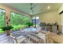 Enclosed patio with ceiling fan, dining set, built-in grill, and serene views of the backyard at 15605 Derna Ter, Bradenton, FL 34211