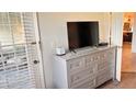 Bedroom featuring light gray dresser with gold hardware and a mounted television at 433 Cerromar Ln # 331, Venice, FL 34293