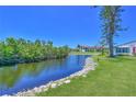 Scenic water view in backyard with lush green grass and rocks and hedges along shoreline at 4726 Potomac Cir, Bradenton, FL 34210
