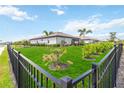 Lush backyard featuring manicured lawn and palm trees, surrounded by a sleek black fence at 5165 Coral Reef Way, Bradenton, FL 34211