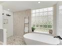 Modern bathroom with a freestanding tub, glass block window, and a stylish shower with sleek fixtures at 6674 Coopers Hawk Ct, Lakewood Ranch, FL 34202