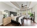 Serene main bedroom with tray ceilings, hardwood floors, and a seating area overlooking the lush backyard at 6674 Coopers Hawk Ct, Lakewood Ranch, FL 34202
