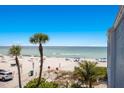Beachside view featuring soft sand and clear water with palm trees and parked cars at 7000 Gulf Dr # 205, Holmes Beach, FL 34217