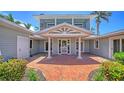 Inviting entryway features a brick pathway, covered porch with columns, and lush tropical landscaping at 878 Freeling Dr, Sarasota, FL 34242