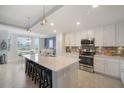 Bright kitchen features modern white cabinets, stainless steel appliances, and a center island with bar seating at 910 Tidewater Shores Loop # 103, Bradenton, FL 34208