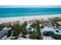 Stunning aerial view of a beachfront home with a pool, clear blue water, and white sandy beach at 102 & 104 48Th St, Holmes Beach, FL 34217