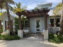Inviting entrance with trellis, stone columns, and a cozy bench overlooking the tropical garden at 102 & 104 48Th St, Holmes Beach, FL 34217