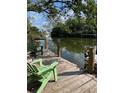 Beautiful backyard dock with lovely chairs and views of calm waters surrounded by lush greenery at 120 Hammock Rd, Anna Maria, FL 34216