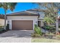 Charming two-story home featuring a brick driveway, lush landscaping, and beautiful, neutral exterior paint at 12822 Del Corso Loop, Bradenton, FL 34211