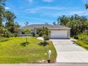 Inviting one-story home with lush green lawn, mature trees, and a convenient two-car garage at 1298 Russellville St, North Port, FL 34288