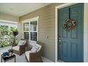 Inviting front porch featuring two chairs, a small table, and a beautifully decorated front door with a wreath at 1739 Lake Verona Cir, Bradenton, FL 34211