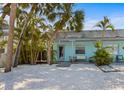 Inviting single-story home with a light-blue exterior, quaint porch, and a beautifully landscaped yard filled with tropical plants at 205 71St St # B, Holmes Beach, FL 34217