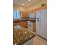 Spacious kitchen with stainless steel appliances, granite countertops, wooden cabinets, and tile flooring at 24028 Park Place S Dr # 32, Punta Gorda, FL 33980