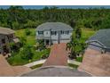Aerial view of a well-manicured home featuring a three-car garage and lush landscaping with beautiful palm trees at 5805 49Th E Ct, Ellenton, FL 34222
