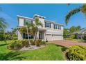 Beautiful home featuring a three-car garage, lush landscaping, palm trees, and a brick driveway at 5805 49Th E Ct, Ellenton, FL 34222