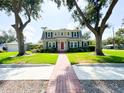 Charming two-story home with a well-maintained lawn and landscaped front yard and a brick walkway leading up to the front door at 708 32Nd W St, Bradenton, FL 34205