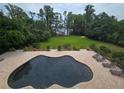 Aerial view of a freeform pool surrounded by brick pavers, lounge chairs, and lush green lawn at 7732 N Mobley Rd, Odessa, FL 33556