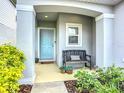 Inviting front porch with bench, flower pots, and view of an attractive, light blue front door at 11015 High Noon Trl, Parrish, FL 34219
