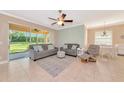 Bright living room with comfortable seating, tile flooring, and a view of the landscaped backyard through sliding doors at 11455 52Nd E Ct, Parrish, FL 34219