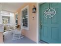 Inviting front porch featuring rocking chairs, coastal decor, and a charming blue front door at 12520 Shimmering Oak Cir, Venice, FL 34293
