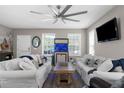 Cozy living room with white sofas, modern ceiling fan, and a wall-mounted TV for entertainment at 12520 Shimmering Oak Cir, Venice, FL 34293
