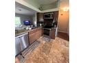 Well-equipped kitchen with stainless steel appliances, tiled floors, granite countertops, and wooden cabinets at 14432 Mcclellan Ave, Port Charlotte, FL 33953