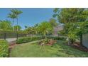 Well-manicured front yard with lush green grass, tropical palm trees, and a charming black metal fence at 1934 Bougainvillea St, Sarasota, FL 34239
