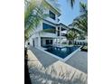 A modern pool and spiral staircase highlight a spacious backyard, framed by tropical plants at 2809 Avenue E, Holmes Beach, FL 34217
