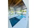 An outdoor living space featuring a modern pool with integrated spa and dark wood ceilings at 2809 Avenue E, Holmes Beach, FL 34217